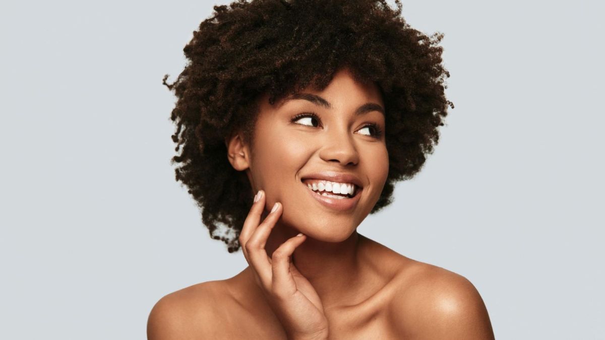 Mulher de pele negra sorrindo com a mão no rosto