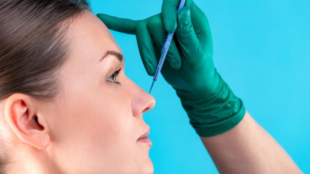 Cirurgião plástico analisando nariz de paciente no pós-operatório da rinoplastia