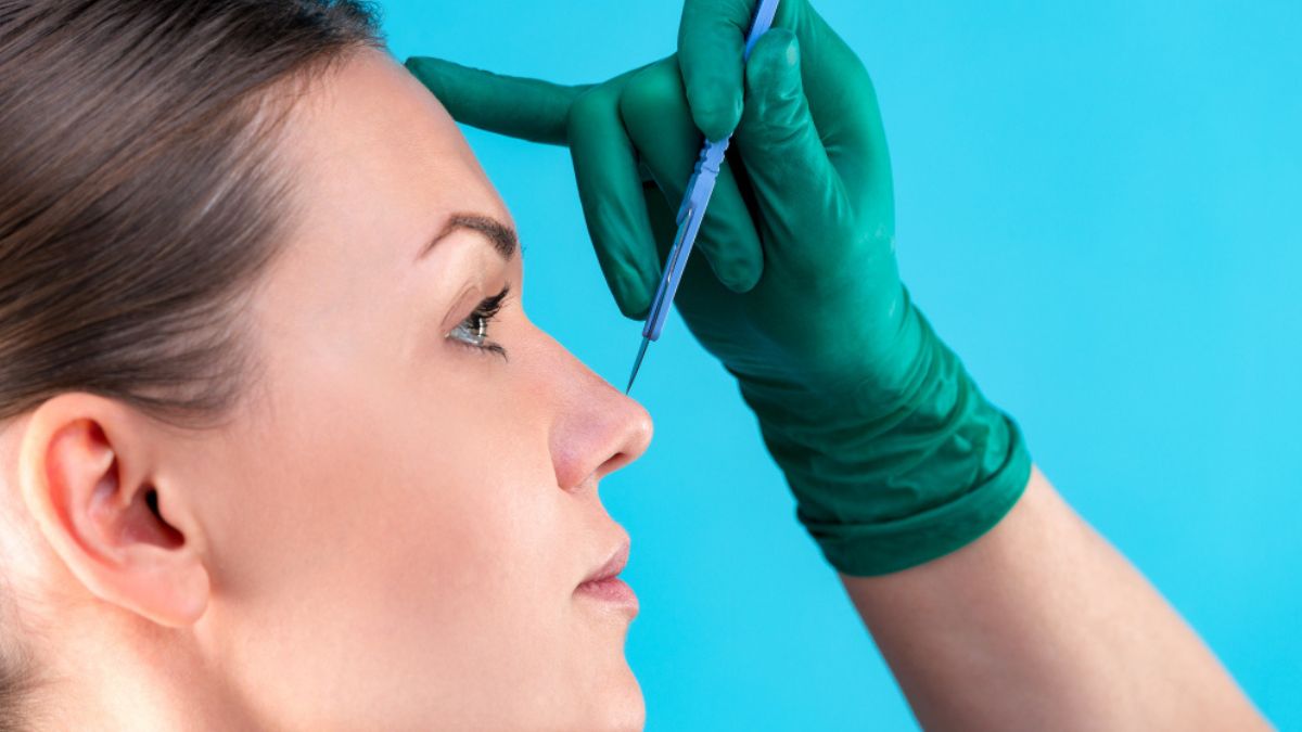 Cirurgião plástico analisando nariz de paciente no pós-operatório da rinoplastia