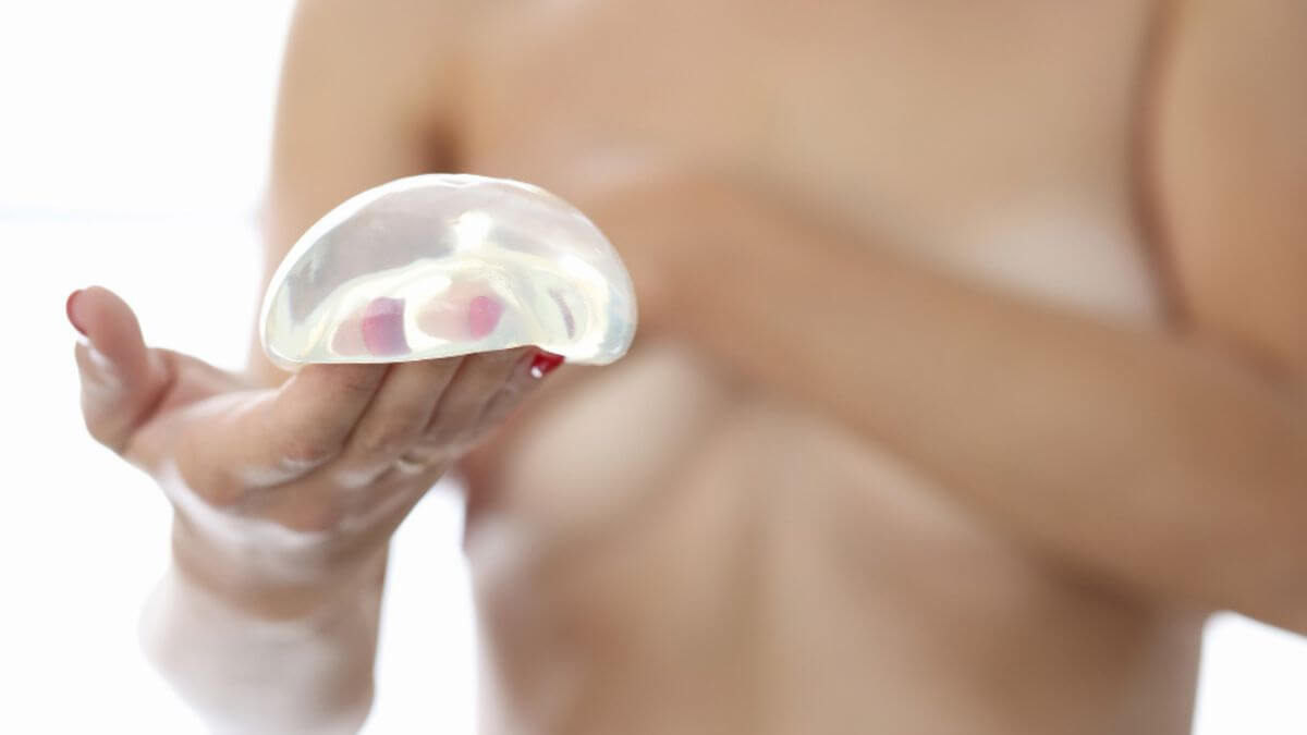 Mulher com corpo desfocado segurando prótese de silicone