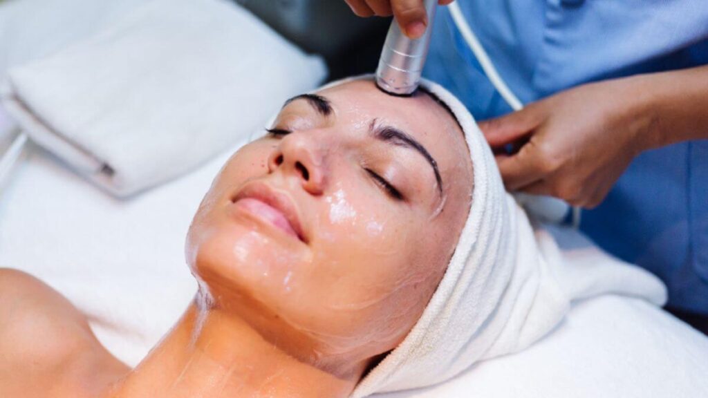 Mulher deitada enquanto esteticista passa peeling químico no rosto dela